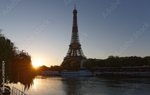 Romantic sunrise background. Eiffel Tower with boats on Seine river in Paris .