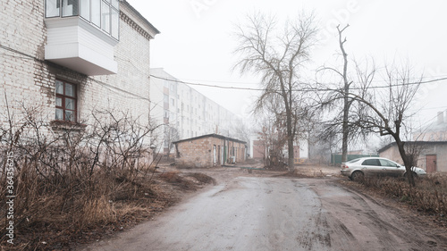 Fototapeta Naklejka Na Ścianę i Meble -  Foggy morning in a provincial Russian city. Barns, houses, car.