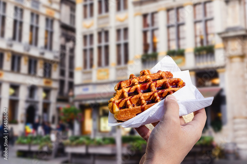 Man holds waffle with chocolate sauce on the background of city