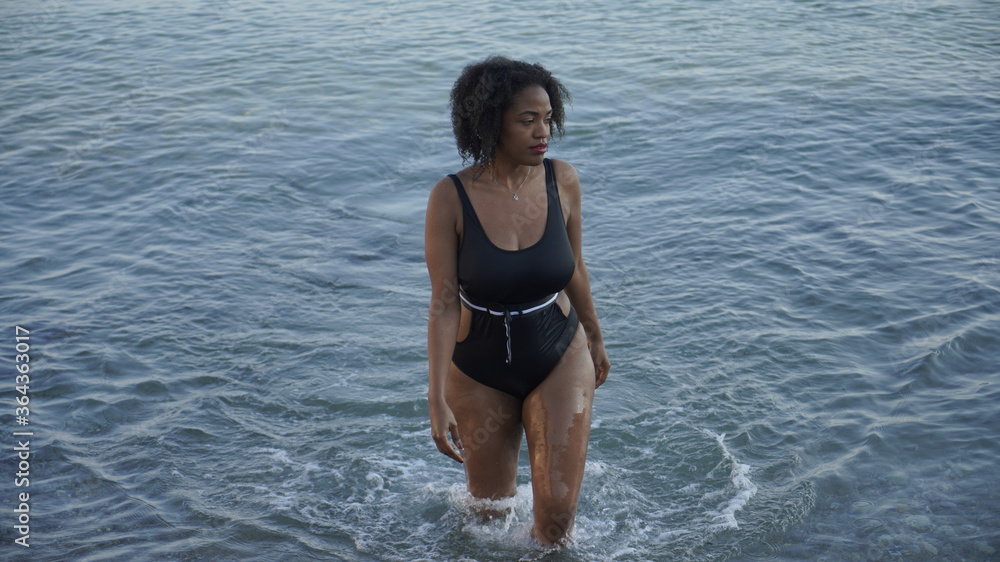 young african american woman walking in the sea.Young woman walks into the cold water on the beach	