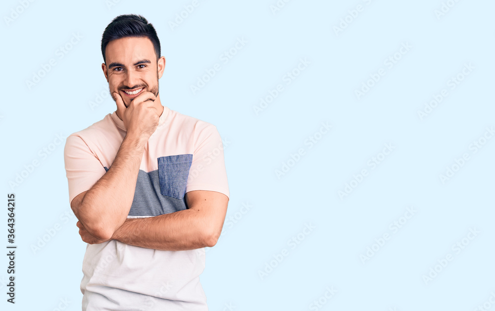 Young handsome man wearing casual clothes looking confident at the camera smiling with crossed arms and hand raised on chin. thinking positive. Young handsome man wearing casual clothes looking confident at the camera smiling with crossed arms and hand raised on chin. thinking positive.