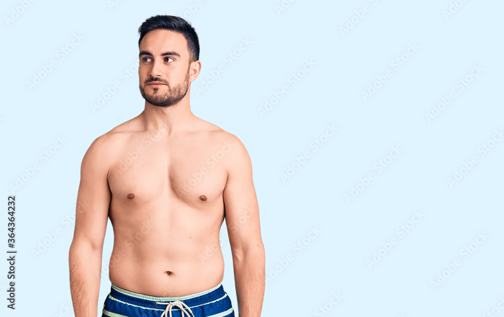 Young handsome man wearing swimwear smiling looking to the side and staring away thinking. Young handsome man wearing swimwear smiling looking to the side and staring away thinking.