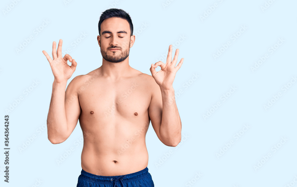 Young handsome man wearing swimwear relax and smiling with eyes closed doing meditation gesture with fingers. yoga concept.