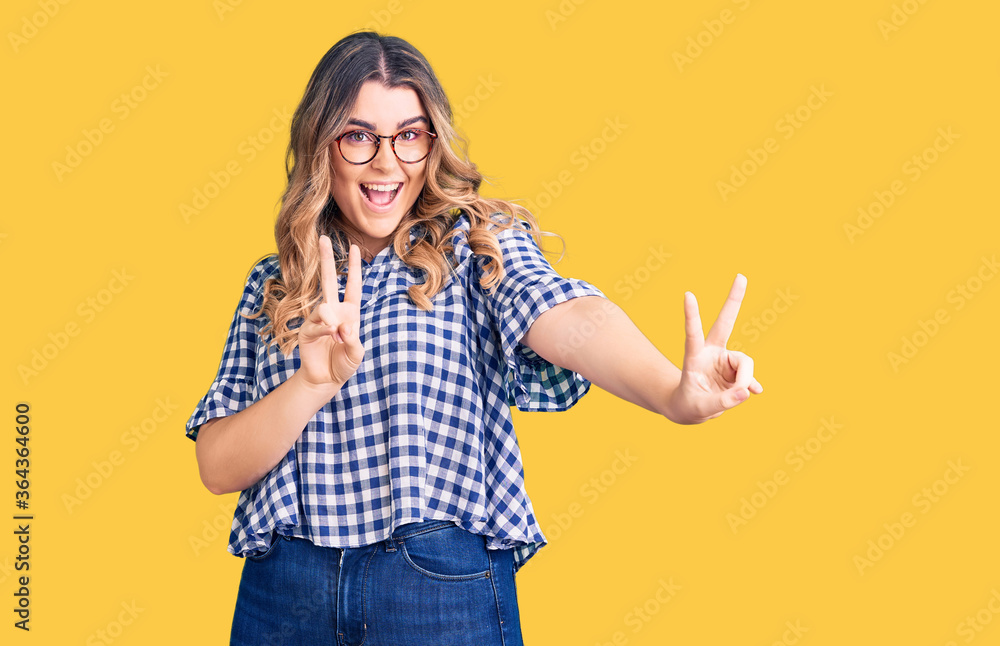 Young caucasian woman wearing casual clothes smiling looking to the camera showing fingers doing victory sign. number two. Young caucasian woman wearing casual clothes smiling looking to the camera showing fingers doing victory sign. number two.