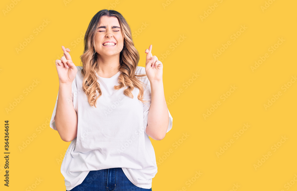 Young caucasian woman wearing casual clothes gesturing finger crossed smiling with hope and eyes closed. luck and superstitious concept. Young caucasian woman wearing casual clothes gesturing finger crossed smiling with hope and eyes closed. luck and superstitious concept.