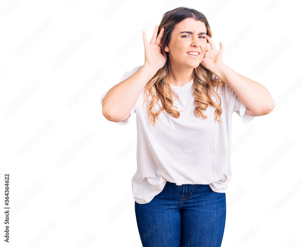 Young caucasian woman wearing casual clothes trying to hear both hands on ear gesture, curious for gossip. hearing problem, deaf Young caucasian woman wearing casual clothes trying to hear both hands on ear gesture, curious for gossip. hearing problem, deaf