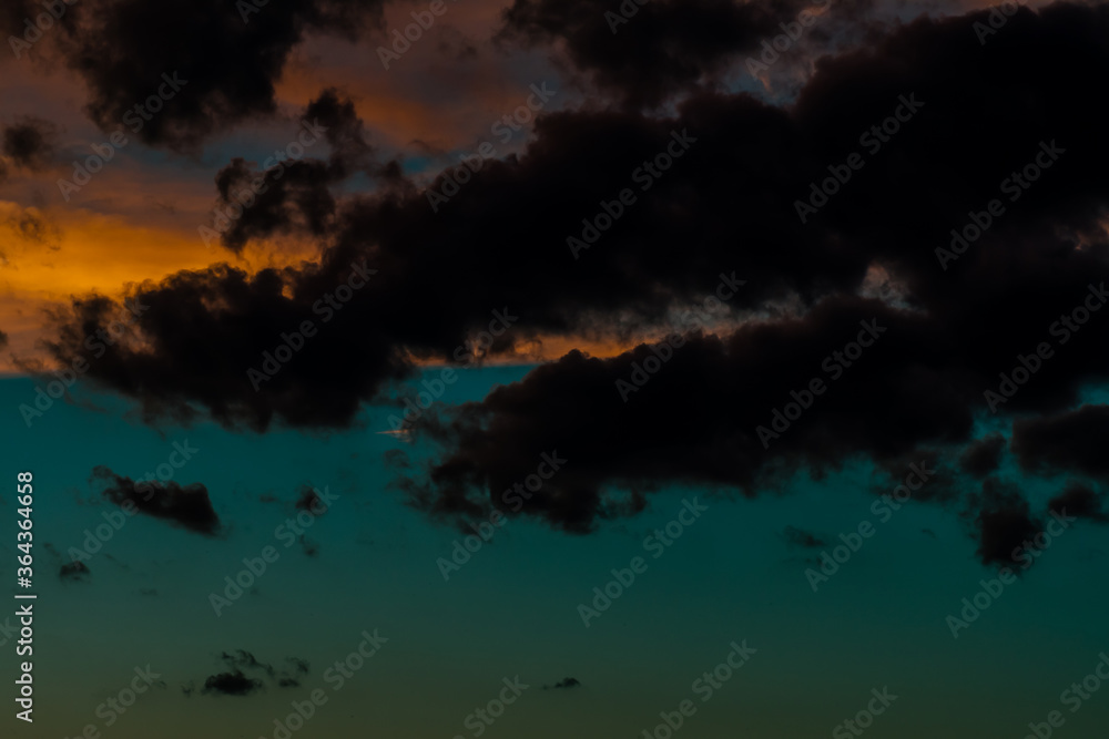 Beautiful dark blue sky at sunset with dark cumulus clouds in front of pink and yellow stratus and cirrus clouds in background. Beautiful dark blue sky at sunset with dark cumulus clouds in front of pink and yellow stratus and cirrus clouds in background.