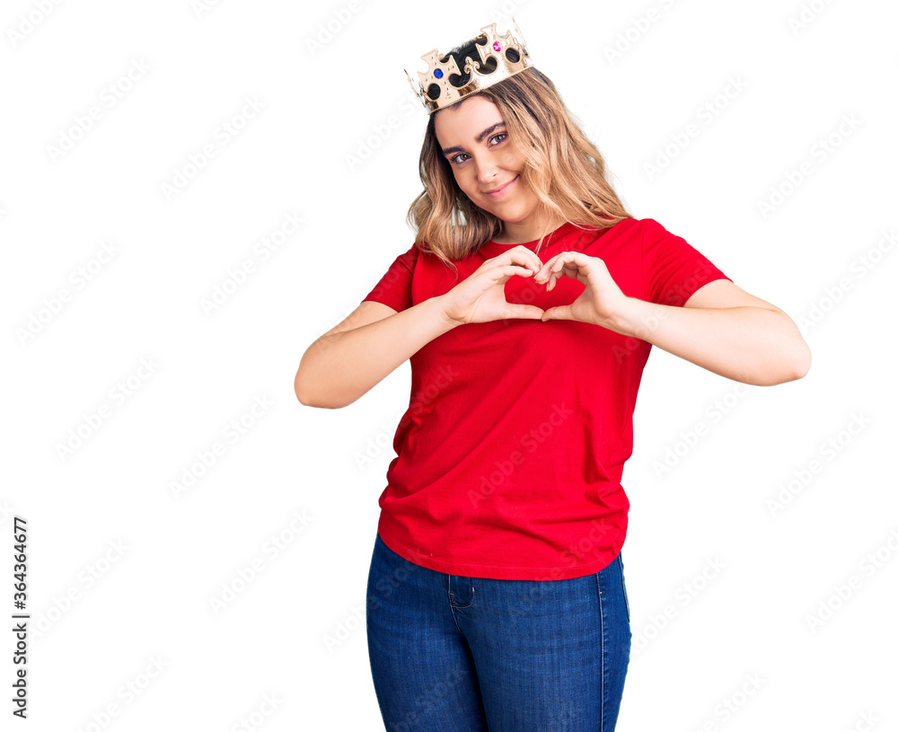 Young caucasian woman wearing princess crown smiling in love showing heart symbol and shape with hands. romantic concept. Young caucasian woman wearing princess crown smiling in love showing heart symbol and shape with hands. romantic concept.