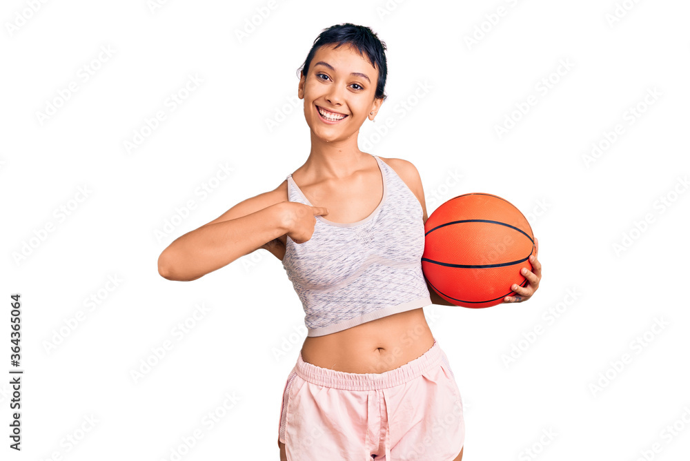 Young woman holding basketball ball pointing finger to one self smiling happy and proud Young woman holding basketball ball pointing finger to one self smiling happy and proud
