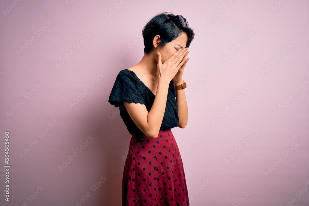 Young beautiful asian girl wearing casual dress standing over isolated pink background with sad expression covering face with hands while crying. Depression concept. Young beautiful asian girl wearing casual dress standing over isolated pink background with sad expression covering face with hands while crying. Depression concept.