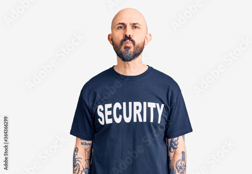 Young handsome man wearing security t shirt looking at the camera blowing a kiss on air being lovely and sexy. love expression.
