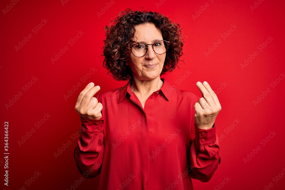 Middle age beautiful curly hair woman wearing casual shirt and glasses over red background doing money gesture with hands, asking for salary payment, millionaire business Middle age beautiful curly hair woman wearing casual shirt and glasses over red background doing money gesture with hands, asking for salary payment, millionaire business