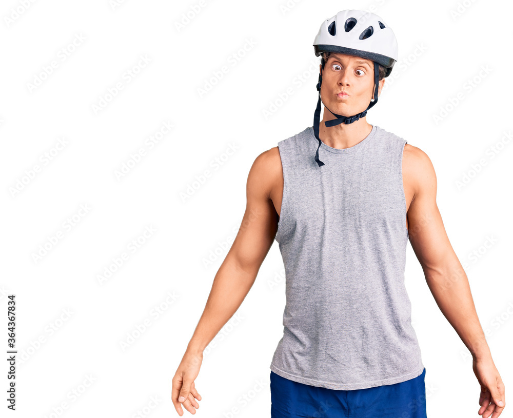 Young handsome man wearing bike helmet making fish face with lips, crazy and comical gesture. funny expression. Young handsome man wearing bike helmet making fish face with lips, crazy and comical gesture. funny expression.
