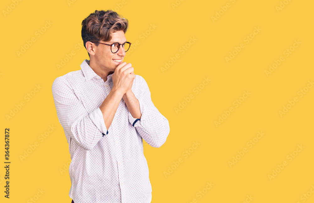 Young handsome man wearing business clothes and glasses laughing nervous and excited with hands on chin looking to the side Young handsome man wearing business clothes and glasses laughing nervous and excited with hands on chin looking to the side