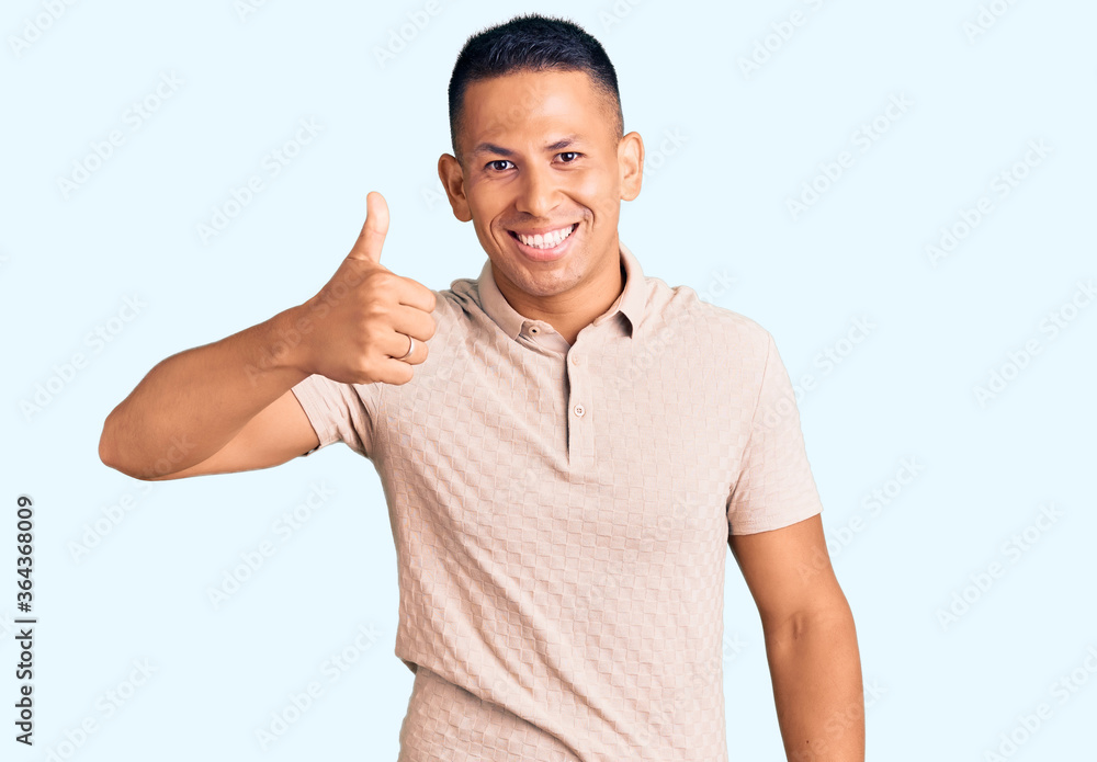 Young handsome latin man wearing casual clothes smiling happy and positive, thumb up doing excellent and approval sign Young handsome latin man wearing casual clothes smiling happy and positive, thumb up doing excellent and approval sign