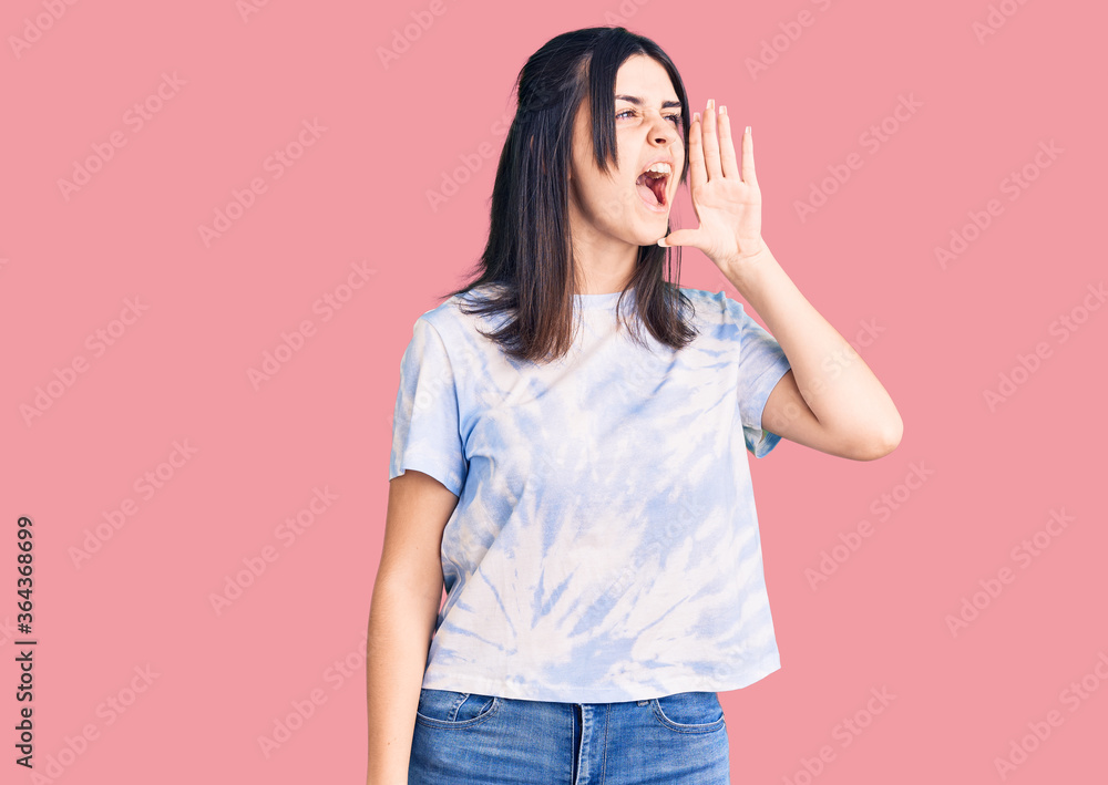 Young beautiful girl wearing casual t shirt shouting and screaming loud to side with hand on mouth. communication concept. Young beautiful girl wearing casual t shirt shouting and screaming loud to side with hand on mouth. communication concept.