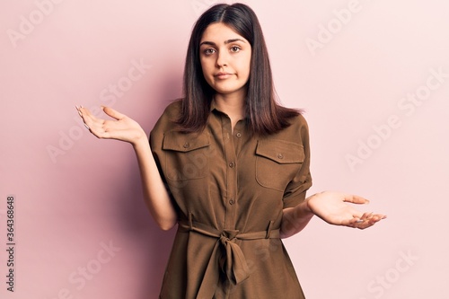фотографія Young beautiful girl wearing casual dress clueless and confused with open arms, no idea and doubtful face