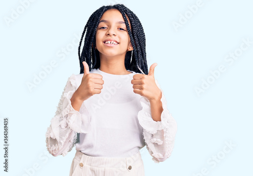 Cute african american girl wearing casual white tshirt success sign doing positive gesture with hand, thumbs up smiling and happy. cheerful expression and winner gesture.