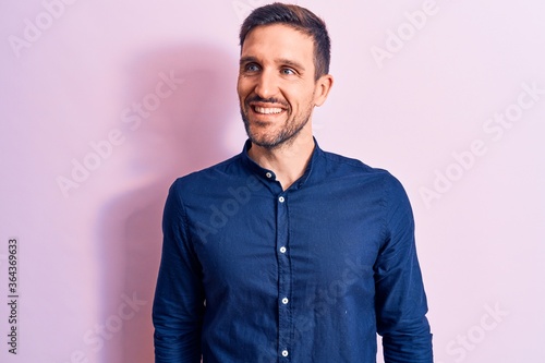 Young handsome man wearing casual shirt standing over isolated pink background looking to side, relax profile pose with natural face and confident smile.