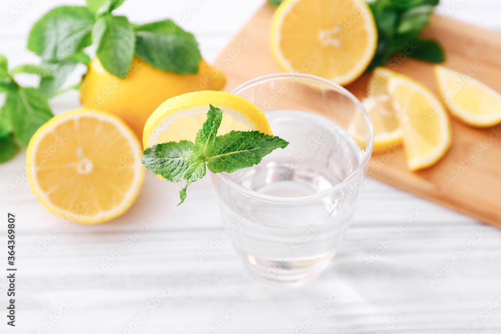Full glass of fresh cool transparent water with lemon and mint leaves on wooden table Full glass of fresh cool transparent water with lemon and mint leaves on wooden table
