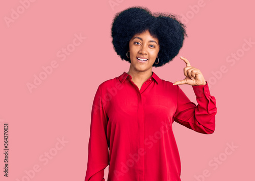 Young african american girl wearing casual clothes smiling and confident gesturing with hand doing small size sign with fingers looking and the camera. measure concept.
