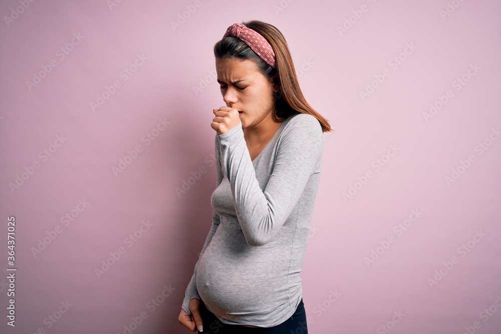 Fototapeta premium Young beautiful teenager girl pregnant expecting baby over isolated pink background feeling unwell and coughing as symptom for cold or bronchitis. Health care concept.