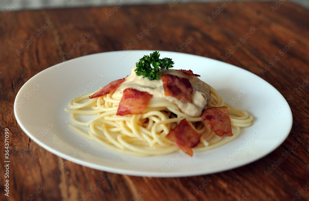 Delicious spaghetti carbonara with bacon on wooden table Delicious spaghetti carbonara with bacon on wooden table