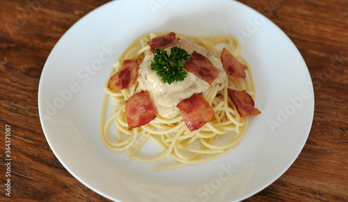 Delicious spaghetti carbonara with bacon on wooden table