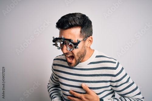 Young handsome man with beard wearing optometry glasses over isolated white background with hand on stomach because nausea, painful disease feeling unwell. Ache concept.