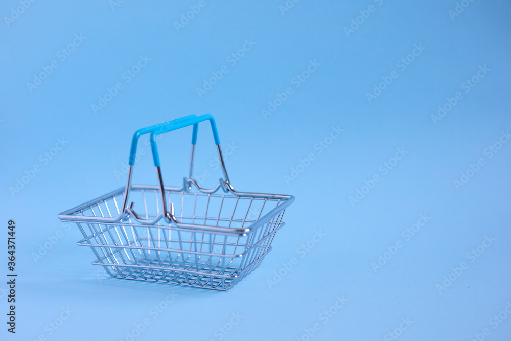 Empty metal shopping basket on a blue background Empty metal shopping basket on a blue background