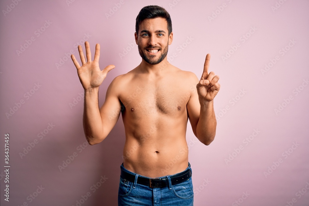 Young handsome strong man with beard shirtless standing over isolated pink background showing and pointing up with fingers number six while smiling confident and happy.