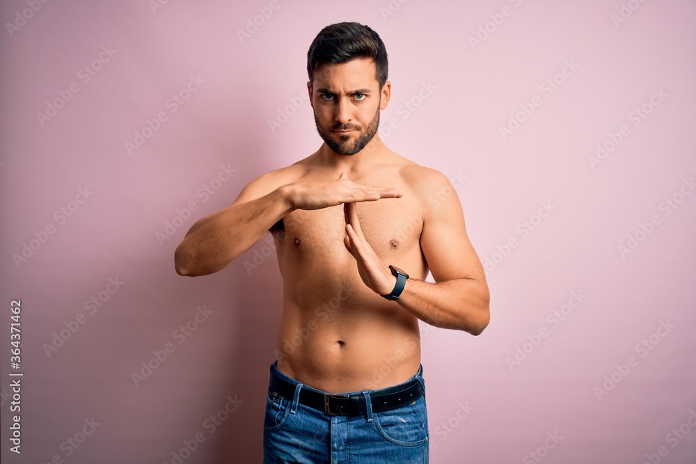 Young handsome strong man with beard shirtless standing over isolated pink background Doing time out gesture with hands, frustrated and serious face