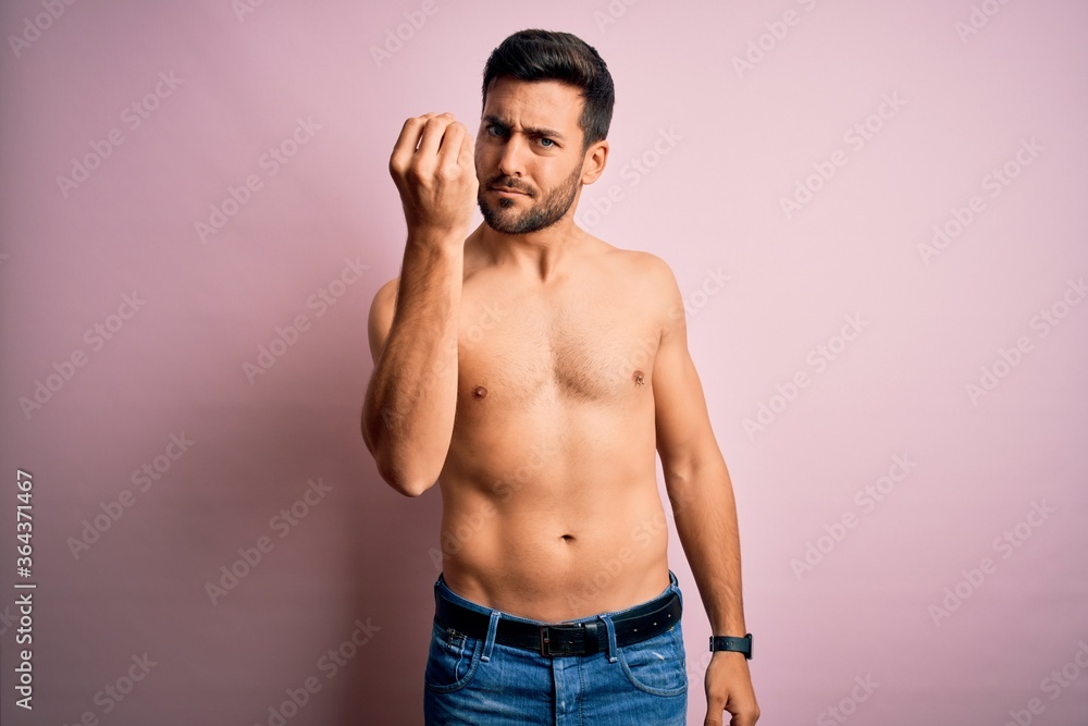 Young handsome strong man with beard shirtless standing over isolated pink background Doing Italian gesture with hand and fingers confident expression