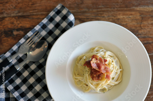 Delicious spaghetti carbonara with bacon on wooden table