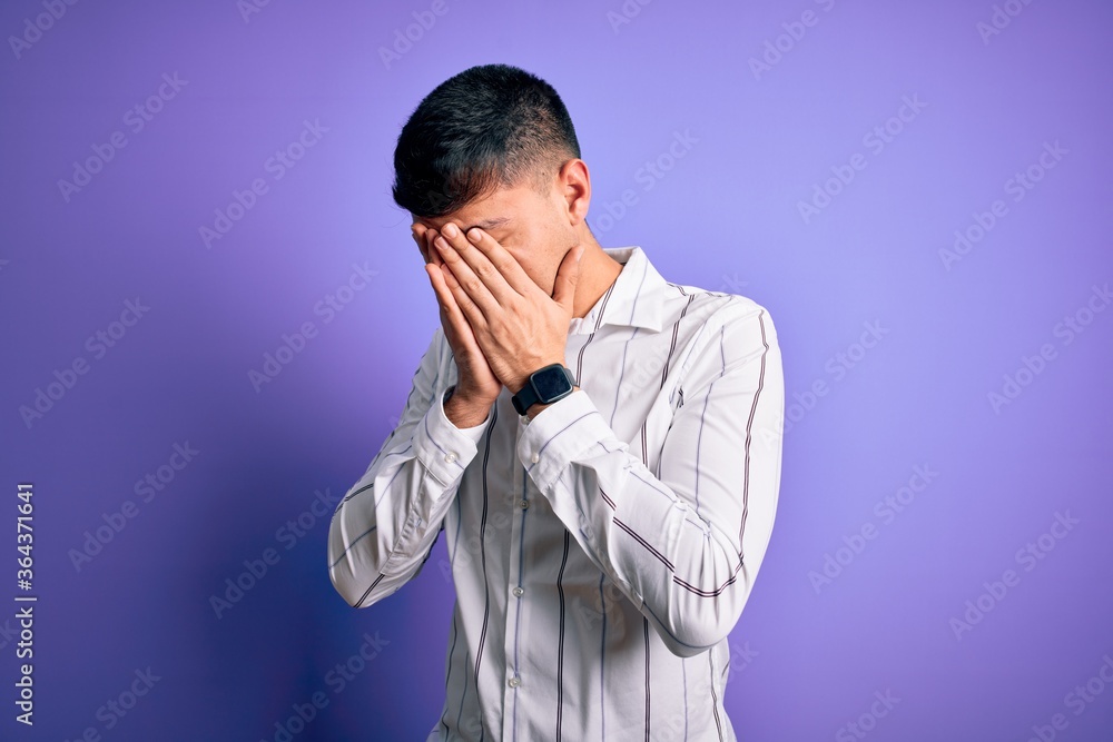Young handsome hispanic man wearing elegant business shirt standing over purple background with sad expression covering face with hands while crying. Depression concept. Young handsome hispanic man wearing elegant business shirt standing over purple background with sad expression covering face with hands while crying. Depression concept.