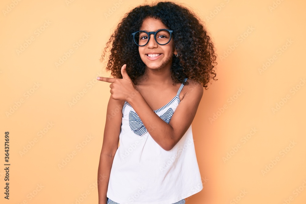 African american child with curly hair wearing casual clothes and glasses smiling cheerful pointing with hand and finger up to the side African american child with curly hair wearing casual clothes and glasses smiling cheerful pointing with hand and finger up to the side
