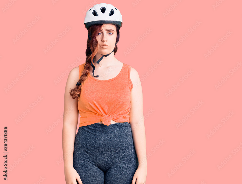 Young beautiful woman wearing bike helmet with serious expression on face. simple and natural looking at the camera. Young beautiful woman wearing bike helmet with serious expression on face. simple and natural looking at the camera.