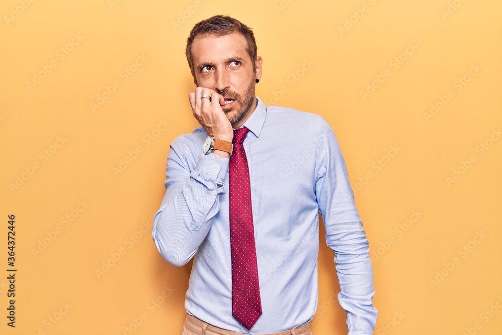 Young handsome man wearing business clothes looking stressed and nervous with hands on mouth biting nails. anxiety problem. Young handsome man wearing business clothes looking stressed and nervous with hands on mouth biting nails. anxiety problem.