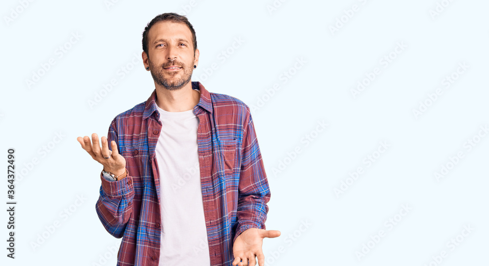 Young handsome man wearing casual clothes smiling cheerful with open arms as friendly welcome, positive and confident greetings Young handsome man wearing casual clothes smiling cheerful with open arms as friendly welcome, positive and confident greetings
