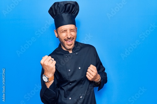 Young handsome man wearing cooker uniform celebrating surprised and amazed for success with arms raised and eyes closed