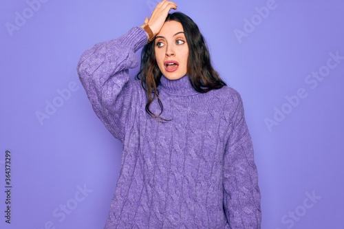 Photos Young beautiful woman wearing casual turtleneck sweater standing over purple background surprised with hand on head for mistake, remember error