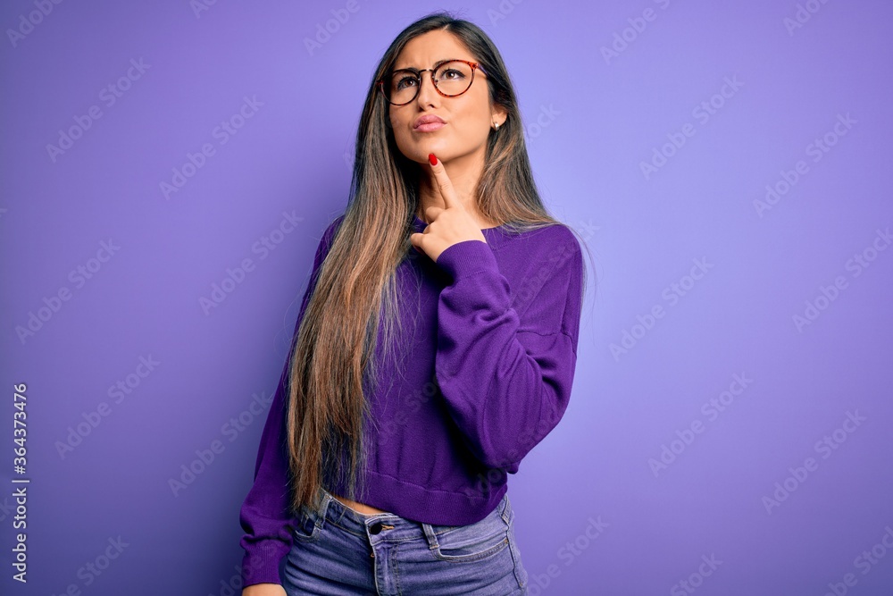 Young beautiful smart woman wearing glasses over purple isolated background Thinking concentrated about doubt with finger on chin and looking up wondering Young beautiful smart woman wearing glasses over purple isolated background Thinking concentrated about doubt with finger on chin and looking up wondering