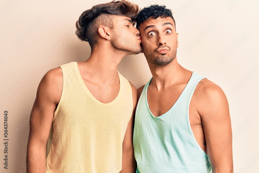 Fototapeta premium Young couple of men wearing summer clothes. Standing with smile on face kissing over isolated white background