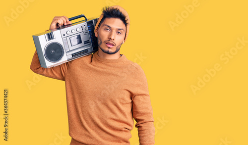 Handsome latin american young man holding boombox, listening to music looking sleepy and tired, exhausted for fatigue and hangover, lazy eyes in the morning.