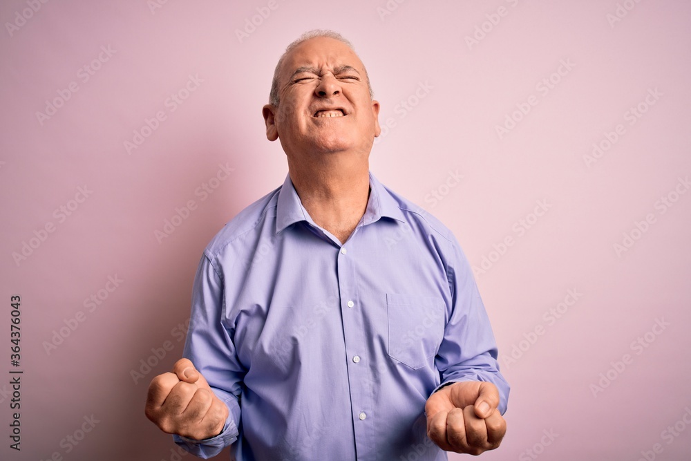 Middle age handsome hoary man wearing casual shirt standing over pink background very happy and excited doing winner gesture with arms raised, smiling and screaming for success. Celebration concept. Middle age handsome hoary man wearing casual shirt standing over pink background very happy and excited doing winner gesture with arms raised, smiling and screaming for success. Celebration concept.