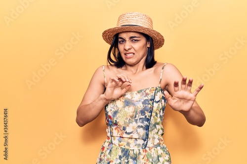 Foto Young beautiful latin woman wearing summer hat disgusted expression, displeased and fearful doing disgust face because aversion reaction