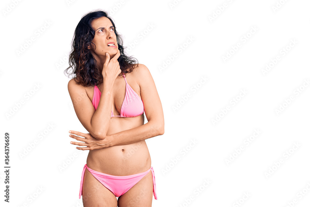 Young beautiful hispanic woman wearing bikini thinking worried about a question, concerned and nervous with hand on chin Young beautiful hispanic woman wearing bikini thinking worried about a question, concerned and nervous with hand on chin