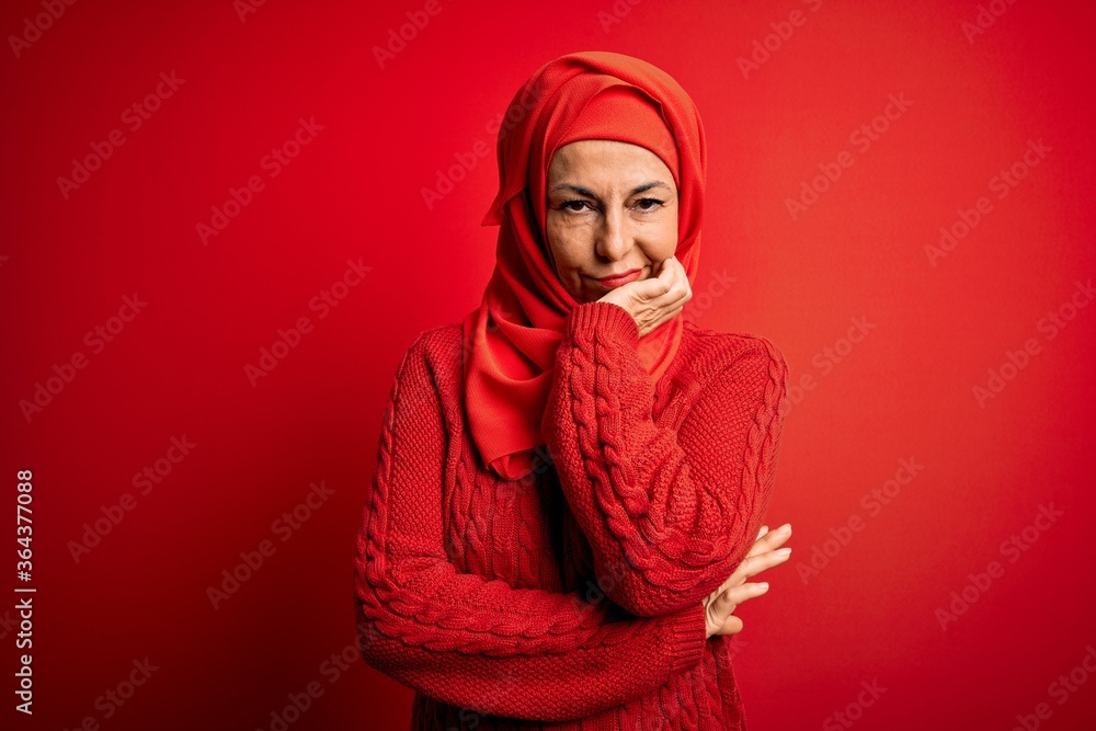 Middle age woman wearing traditional muslim hijab standing over isolated red background thinking looking tired and bored with depression problems with crossed arms. Middle age woman wearing traditional muslim hijab standing over isolated red background thinking looking tired and bored with depression problems with crossed arms.