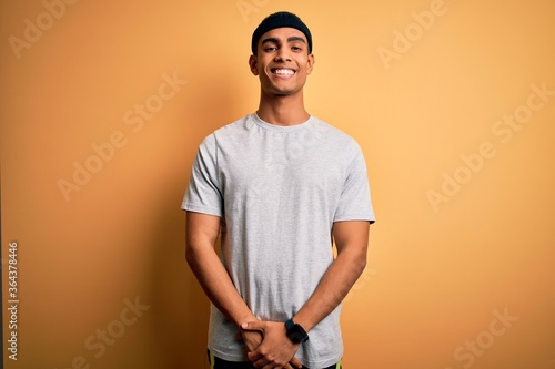 Handsome african american sportsman doing sport wearing sportswear over yellow background with a happy and cool smile on face. Lucky person. © Krakenimages.com