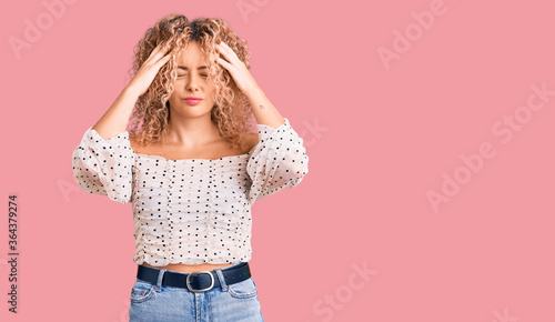 Fotografie Young blonde woman with curly hair wearing casual clothes suffering from headache desperate and stressed because pain and migraine